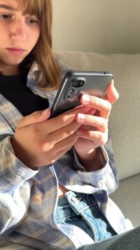 Teenage girl sitting on sofa with smartphone, modern technology, casual relaxation