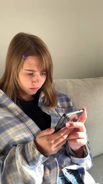 Teenage girl browsing social media on smartphone, couch relaxation, digital era