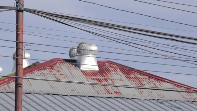 Silver roof turbine ventilators on a rusty corrugated metal roof with power lines