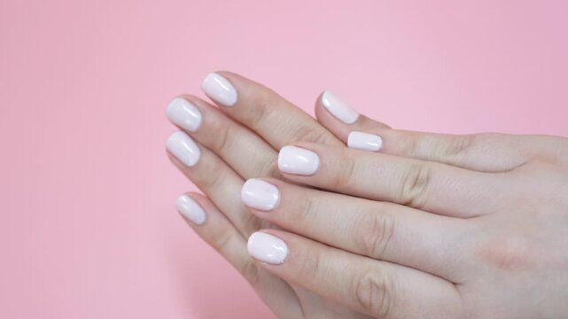Female hands with manicure on pink background.