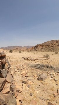 Panning shot of an arid desert landscape featuring rocky terrain and a historic stone circle.