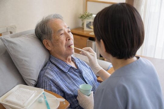 Visiting hygienist providing oral care to an elderly man in bed with soft natural daylight