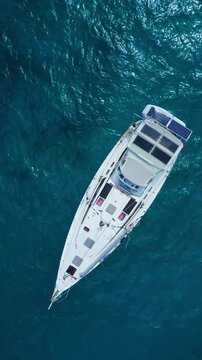 Aerial view yacht solar panels turquoise sea anchored above coral shelf, calm deep blue water, serene sustainable luxury escape, sunlight reflecting on panels, drone perspective, Maldives