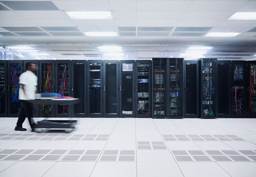 IT Professional Moving Equipment Through Modern Data Center Server Room