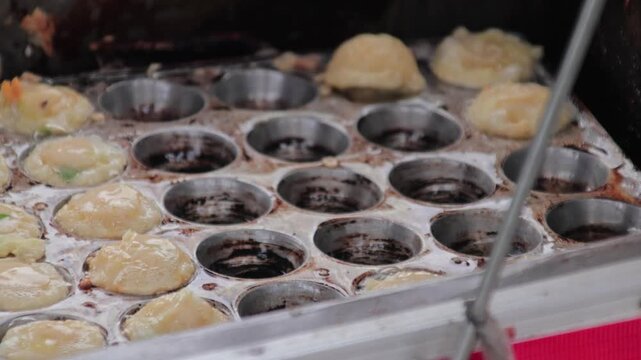 Close up of hand pouring cooking oil from plastic bottle into round pan mold