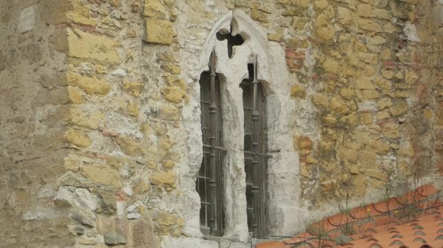 Exterior detail of a mullioned gothic window on the stone facade of a historic Spanish cathedral