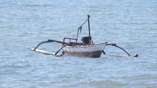 Traditional Balinese fishing boat floating on calm sea