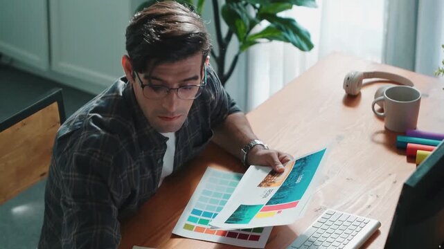 Professional designer writing and designing logo graphic at meeting. Closeup of business man working on colored palettes and writing idea on sticky notes on table with equipment and paper. Symposium.