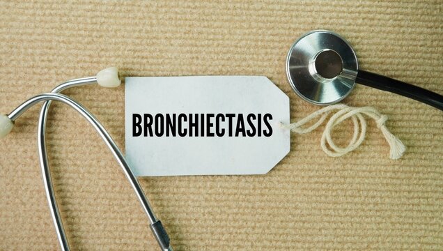 Stethoscope and paper tag with the words Bronchiectasis is a chronic lung condition where the airways bronchi become permanently widened, thickened, and damaged