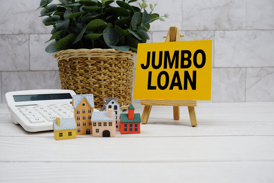 Jumbo Loan text with house model and calculator on wooden background