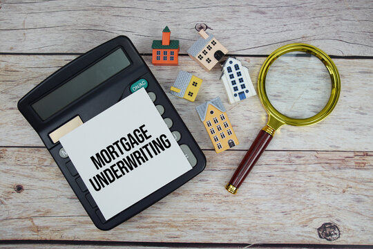 Mortgage Underwriting text with house model, calculator and magnifying glass on wooden background