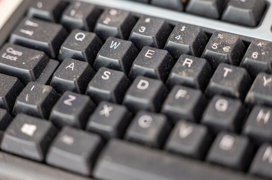 Macro close-up of a dusty black computer keyboard in a woodworking workshop, combining technology, workplace hygiene, maintenance, contamination, industrial work and digital equipment concepts.