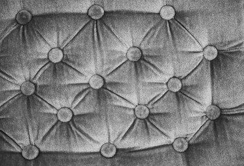 Black and white close-up of button-tufted velvet upholstery, creating an elegant geometric textile texture and vintage furniture background with soft folds and decorative pattern.  © Marek