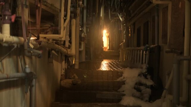 強い明かりに照らされた配管が入り組む温泉街のディープな路地裏のスローモーション