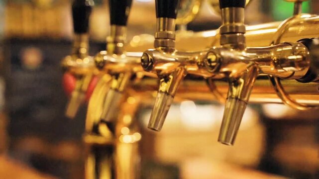 Close-up shot of shiny brass beer taps lined up in a cozy pub or bar, perfect for beverage, pub culture, and nightlife projects.