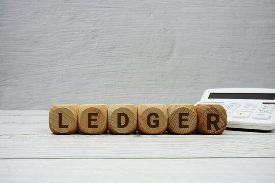 LEDGER alphabet letters with calculator on wooden background