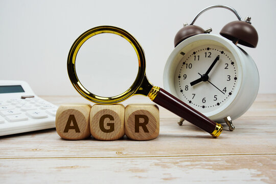 AGR Adjusted Gross Revenue alphabet letters with magnifying glass, calculator and alarm clock