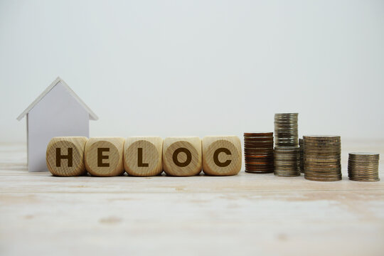 HELOC (Home Equity Lines Of Credit) alphabet letters with house model and coin stack Properties and Real Estate Concept
