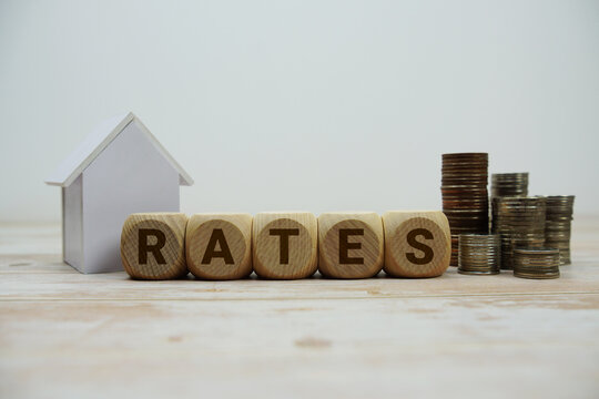 RATES alphabet letters with house model and coin stack Properties and Real Estate Concept