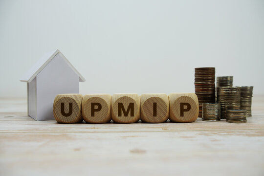 UPMIP (Upfront Mortgage Insurance Premium) alphabet letters with house model and coin stack Properties and Real Estate Concept