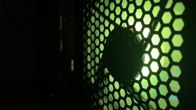 computer fan operating behind black honeycomb mesh grill pattern