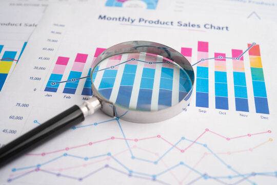 Magnifying glass on data business graphs paper.