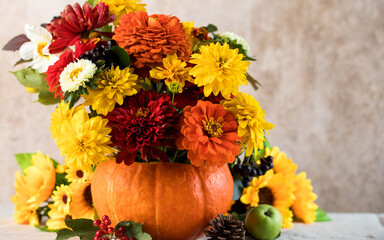 Obraz premium Autumn flower arrangement in pumpkin vase with seasonal harvest decor