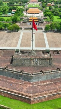 Vertical video, Aerial drone view of Hue Imperial City and historic Flag Tower in Vietnam, showcasing traditional Vietnamese architecture, ancient citadel walls, gardens and cultural heritage.