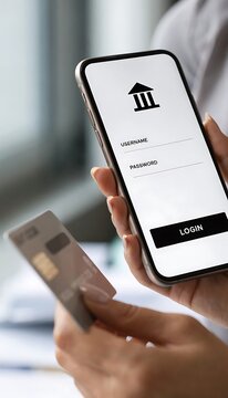 Person holding a smartphone with a banking login screen and a credit card for online payment