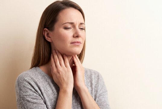 Woman Touching Sore Throat Experiencing Pain From Cold or Flu