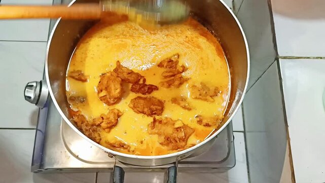 Close up of stir frying Pakistani Dish KAri Pakora  in a deep pan with wooden utensils with showcasing process blending flavors over gas flame sequence cooking ingredients ingredients being stirred