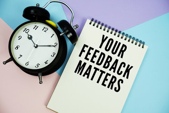 Your Feedback Matters text written on notepad with alarm clock flat lay on multicolor pastel background