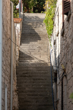 Stone steps leading through a narrow, charming street, creating a peaceful and atmospheric scene with traditional Mediterranean architecture.