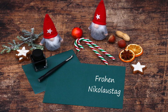  Gru&szlig;karte mit Aufschrift "Frohen Nikolaustag", Wichteln, Zuckerstangen, Tintenfass und Deko auf Holzgrund