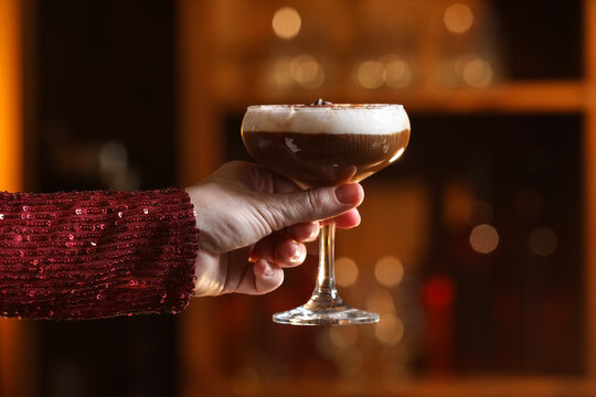 Woman holding glass of tasty tiramisu cocktail in bar
