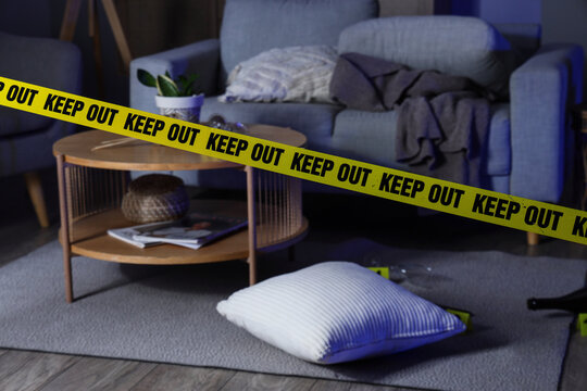 Crime scene investigation and forensic evidence, yellow police tape in a living room with a discarded pillow and evidence markers on the floor