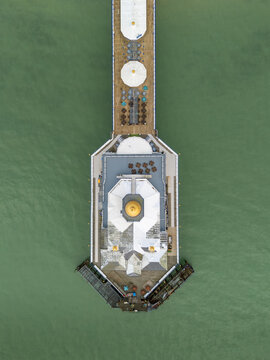 Top-down aerial view of the seaward pavilion end of Eastbourne Pier over green coastal sea waters in East Sussex, England