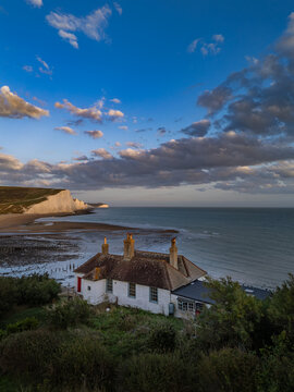 Elevated view of the historic Coastguard Cottages on Short Brow with the Seven Sisters white chalk cliffs and English Channel in the background near Seaford, East Sussex, England