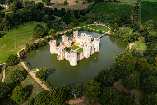 High aerial view of the 14th-century moated Bodiam Castle surrounded by water, green lawns, and woodland near Robertsbridge in East Sussex, England
