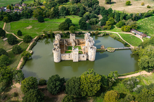 High aerial view of the 14th-century moated Bodiam Castle surrounded by water, green lawns, and woodland near Robertsbridge in East Sussex, England