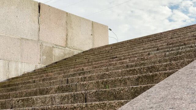 Wide granite stairs lead upward beside a stone wall in Saint Petersburg. The empty steps create a quiet and peaceful mood under a soft sky.