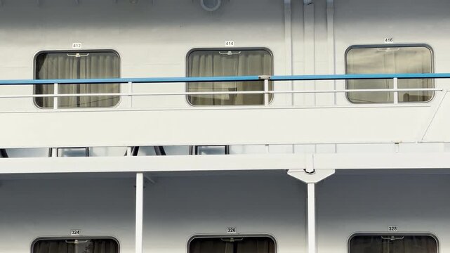 A white passenger ship rests quietly at the harbor in Saint Petersburg. Its numbered cabin windows look peaceful and inviting under soft daylight. The calm scene evokes a gentle feeling of cozy wonder