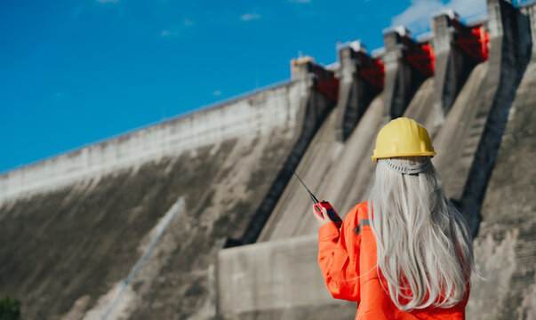Professional engineer inspecting water supply industry dam site feeling confident and focused while working at power station area facility