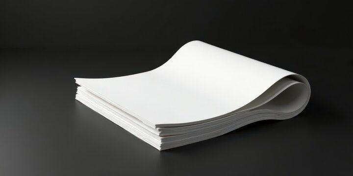 A stack of blank white papers elegantly curved on a dark surface, ready for your design or text.