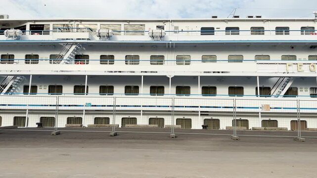 A large passenger ship stands docked behind a fence in Saint Petersburg. It waits quietly for an exciting trip. The peaceful scene brings a calm feeling.
