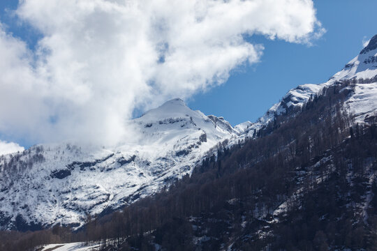 Snow blankets rugged mountain peaks under blue sky