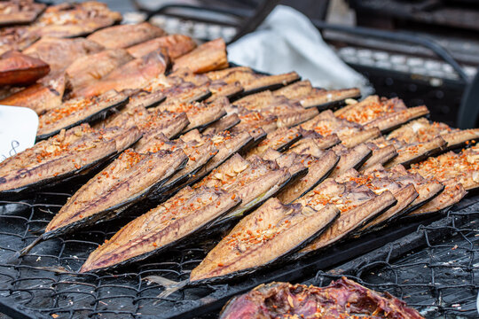 Close-up of smoked mackerel fish fillets displayed on a rack in a farmer street market, ready to eat
