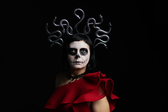 Day of the Dead or Halloween themed image with a woman with skull painting on her face and a skull.	