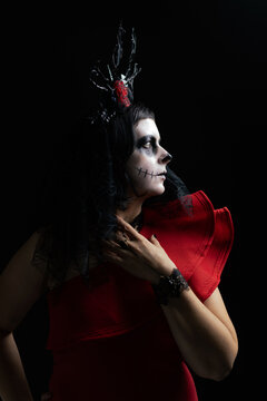 Day of the Dead or Halloween themed image with a woman with skull painting on her face and a skull.	