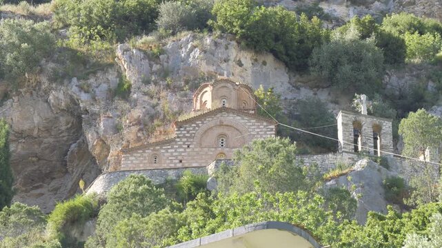 Camera tilts down from the rocky cliff to St. Michael's Church and its bell tower set in the hillside greenery.